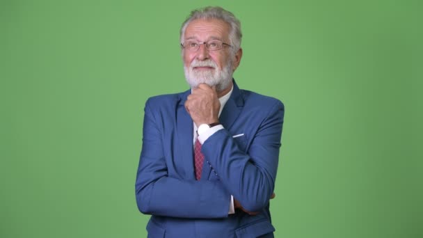 Handsome senior bearded businessman against green background — Stock Video