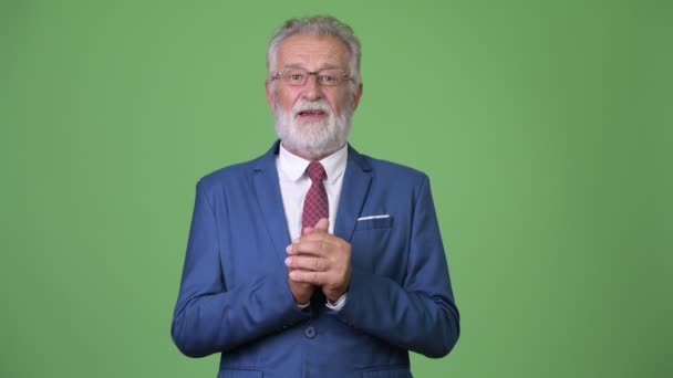 Handsome senior bearded businessman against green background — Stock Video