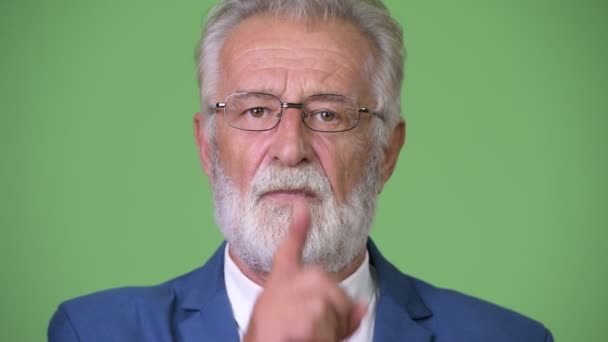 Handsome senior bearded businessman against green background — Stock Video