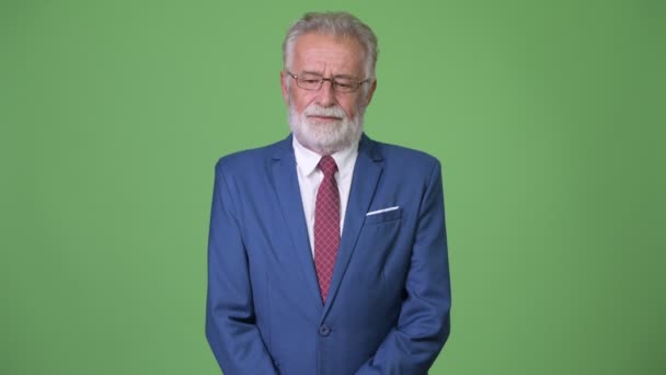 Handsome senior bearded businessman against green background — Stock Video