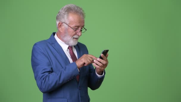 Handsome senior bearded businessman against green background — Stock Video