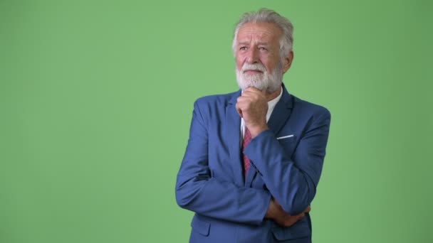 Handsome senior bearded businessman against green background — Stock Video