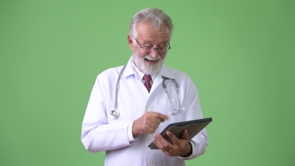 초록색 배경에 대처하기 위해 턱수염을 기르는 노인 의사 — 비디오