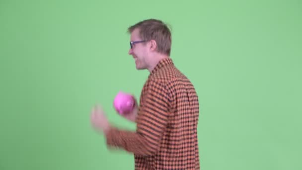Boldog fiatal hipszter férfi megfordul, miközben a malacperselyt fogja és táncol — Stock videók