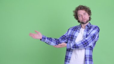 Stresli genç sakallı hippi bir şey gösteriyor ve başparmağını kaldırıyor.