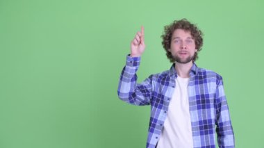 Genç ve mutlu sakallı hippi adam yukarı işaret ederken düşünüyor.