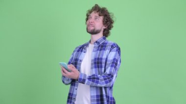 Mutlu genç sakallı hippi telefon kullanırken düşünüyor.