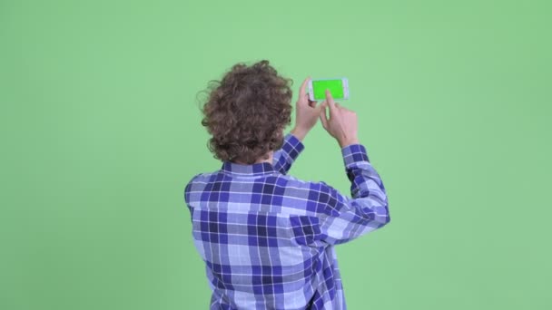 Rückansicht junger bärtiger Hipster-Mann beim Fotografieren mit dem Handy — Stockvideo