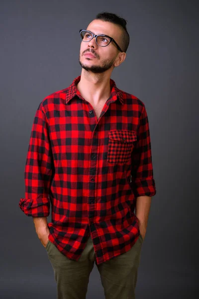 Studio shot of handsome Turkish man wearing eyeglasses against gray background