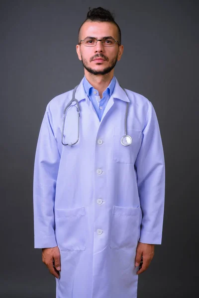 Studio shot of handsome Turkish man doctor against gray background