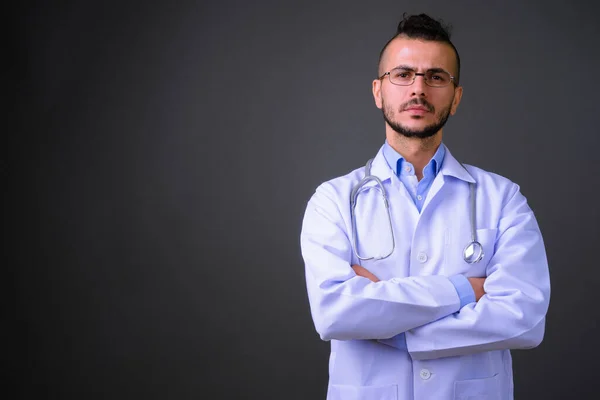 Studio shot of handsome Turkish man doctor against gray background