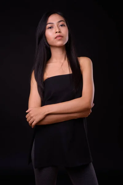 Porträtt av ung vacker asiatisk kvinna med armarna korsade — Stockfoto