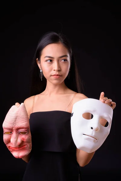 Ritratto di giovane donna asiatica che sceglie tra due maschere — Foto Stock