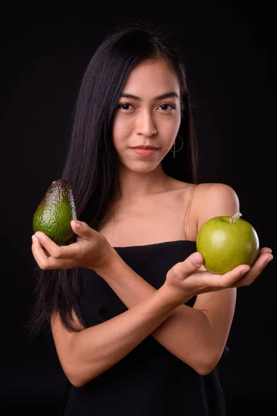 Portrait of young beautiful Asian woman with apple and avocado — Stock Photo, Image