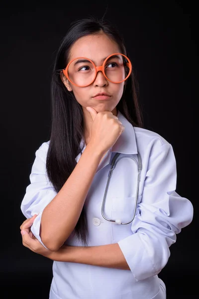Ung asiatisk kvinna läkare med glasögon tänker — Stockfoto