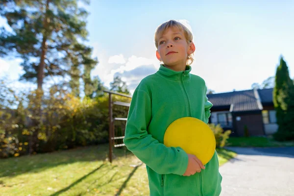 Mladý pohledný chlapec hraje frisbee v přední zahradě — Stock fotografie
