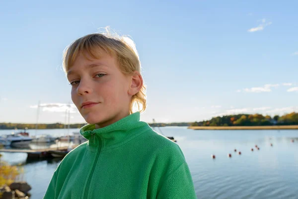 Mladý pohledný chlapec proti pohledu na dřevěné molo u řeky — Stock fotografie