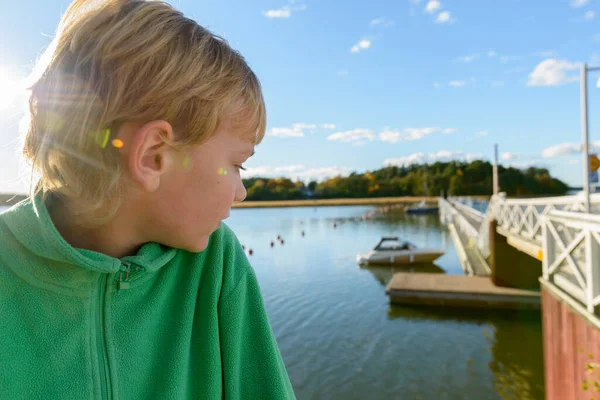Profil pohled na mladého pohledného chlapce při pohledu na dřevěné molo u řeky — Stock fotografie