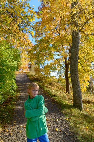 Mladý pohledný chlapec se zkříženýma rukama v parku na podzim — Stock fotografie