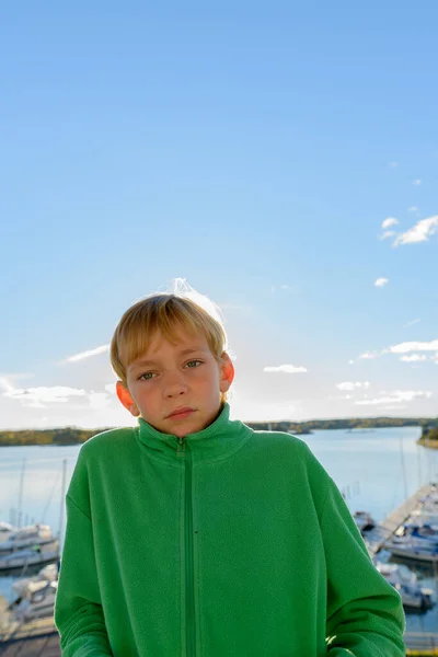 Mladý pohledný chlapec proti pohledu na dřevěné molo u řeky — Stock fotografie