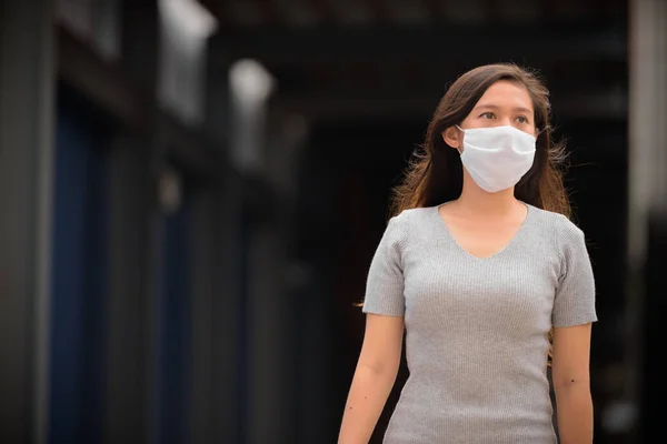 Fiatal ázsiai nő gondolkodás maszk elleni védelem koronavírus kitörése szabadban — Stock Fotó