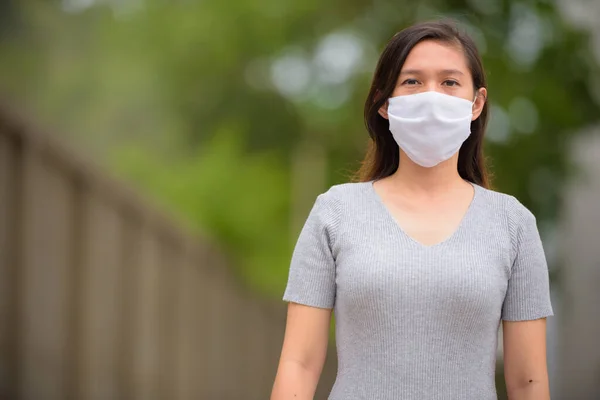 Fiatal ázsiai nő maszkot visel a koronavírus elleni védelem érdekében a szabadban — Stock Fotó