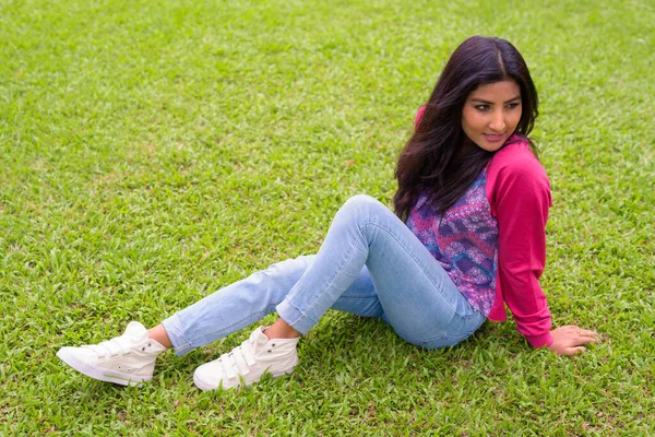 Portrait of young beautiful Persian woman relaxing at the park