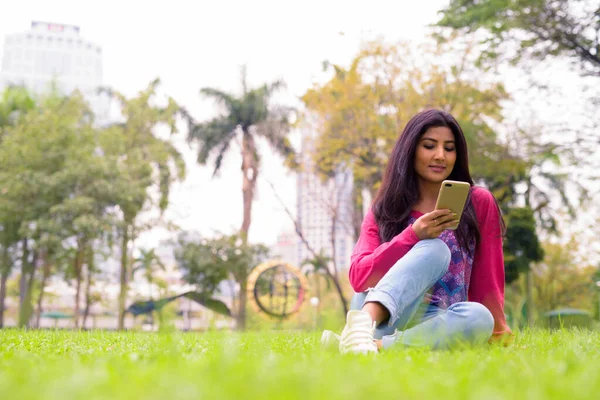 Portrait of young beautiful Persian woman relaxing at the park