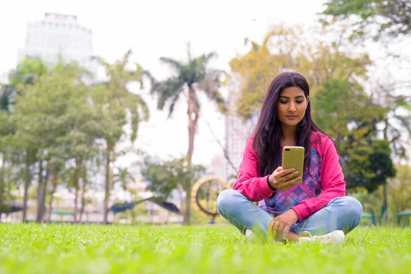 Portrait of young beautiful Persian woman relaxing at the park