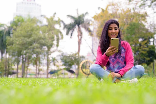 Portrait of young beautiful Persian woman relaxing at the park