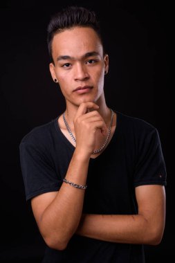 Siyah arka planda genç ve yakışıklı Hintli adamın stüdyo fotoğrafı.