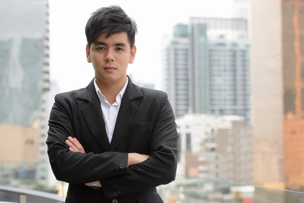 Portrait of young handsome Filipino businessman against view of the city outdoors