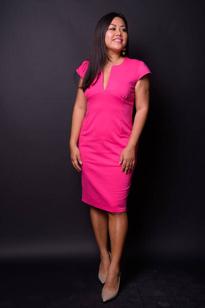 Studio shot of beautiful overweight Asian woman against black background