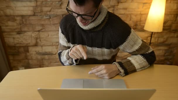 Stressed young man looking disgusted while using laptop at home — Stock Video