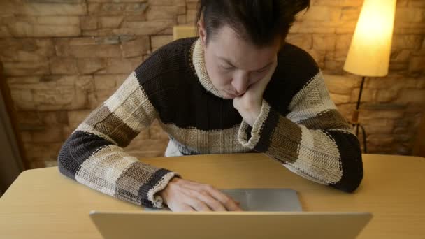 Gestresste jonge man op zoek verdrietig en eenzaam tijdens het gebruik van laptop thuis — Stockvideo