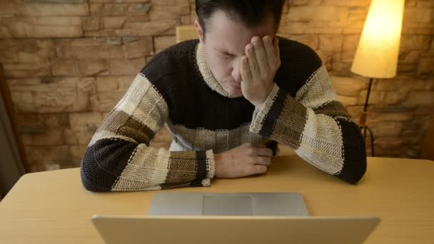 Hombre joven estresado que tiene dolor de cabeza mientras usa el ordenador portátil en casa — Vídeo de stock