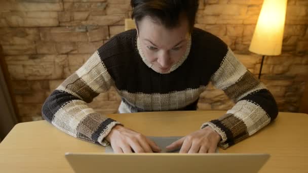 Gelukkig jonge man op zoek verrast tijdens het gebruik van laptop thuis — Stockvideo