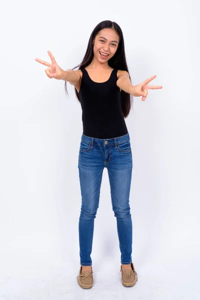 Corpo inteiro tiro de feliz jovem mulher asiática com sinal de paz — Fotografia de Stock