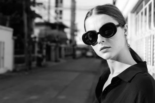 Portrait of young beautiful woman as secret agent in the city streets outdoors in black and white