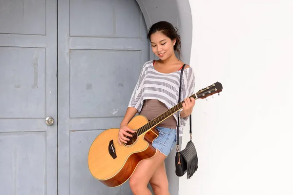 若い美しいアジアの女性の肖像 屋外の街でギターを演奏 — ストック写真