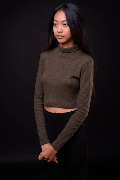 演播室拍摄的年轻美丽的亚洲女人穿着黑色背景的高领毛衣 — 图库照片