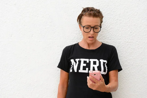 Portrait of mature beautiful nerd woman wearing eyeglasses against white background outdoors