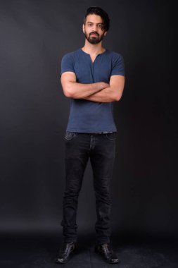 Siyah arka planda yakışıklı sakallı İranlı adamın stüdyo fotoğrafı.