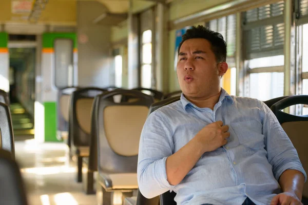 Portrait of young handsome overweight Filipino tourist man riding inside the train