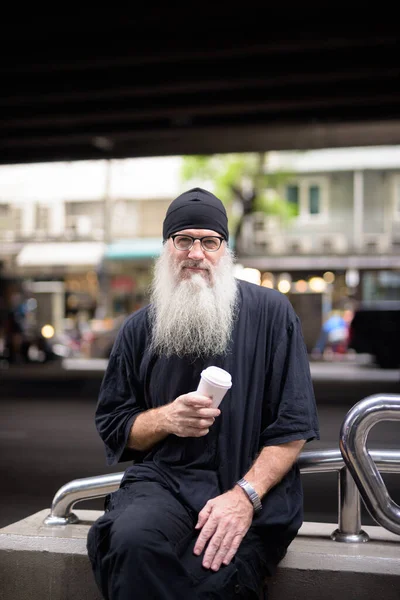 Portrait of mature handsome bearded hipster man in the city streets outdoors