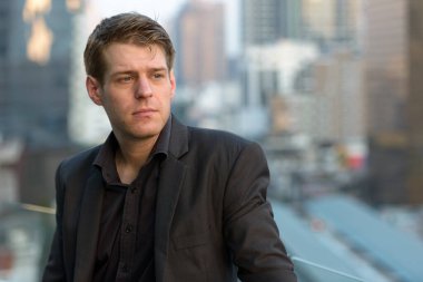Portrait of young handsome businessman in suit against view of the city