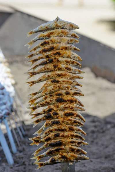 Portrait of freshly caught sea fish grilled on stick sprinkled with salt