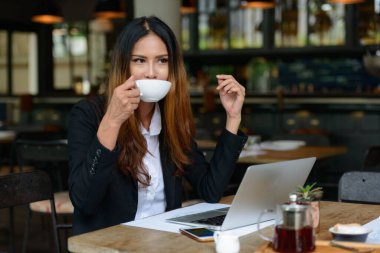 Portrait of young beautiful Asian businesswoman working at the coffee shop