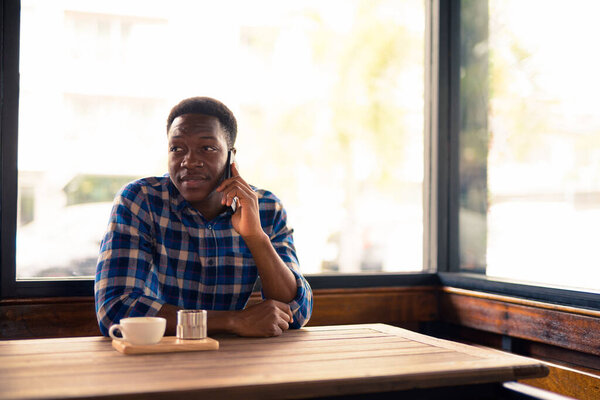 Portrait of young handsome African man relaxing at the coffee shop