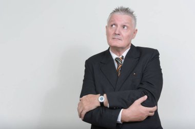 Beyaz arka planda gri saçlı, takım elbiseli kıdemli işadamının stüdyo fotoğrafı.